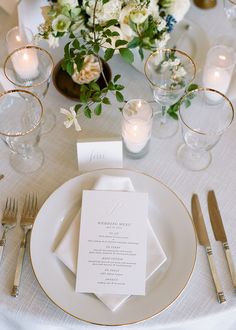 the table is set with white and gold place settings, silverware, and floral centerpieces