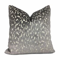 a gray and white pillow with black spots on the front, sitting on a white background