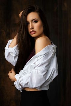 a woman with long brown hair wearing a white shirt and black skirt posing for a photo