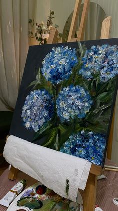 a painting on an easel with blue flowers in it