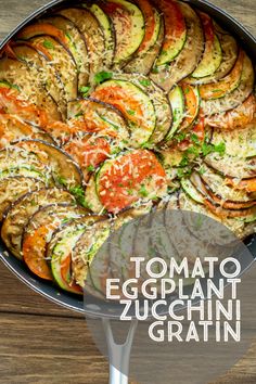 an eggplant, zucchini and tomato dish in a pan on a wooden table