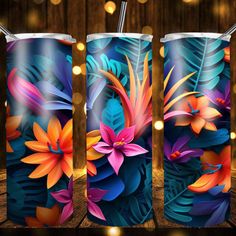 three colorful tumbles with flowers and leaves on them, one has a straw in it