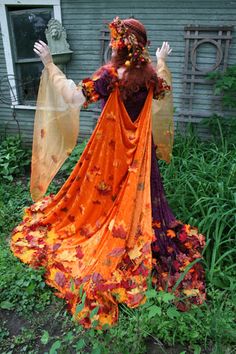 a woman dressed in an orange and purple costume with her hands out to the side