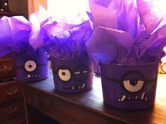 three purple plastic cups with tissue paper in them and eyes painted on the sides, sitting on a table