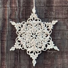 a crocheted snowflake hanging on a wooden surface