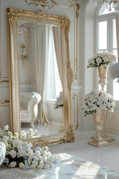 a large mirror sitting on top of a floor next to a vase filled with flowers