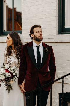 the bride and groom are walking down the stairs together in their red velvet tuxedo