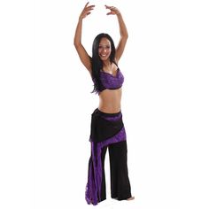 a woman in a purple top and black pants is dancing with her hands up to the side