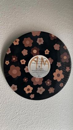 a black and brown flowered plate hanging on the wall next to a white wall