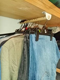 clothes hanging on hooks in a closet next to a baseball bat