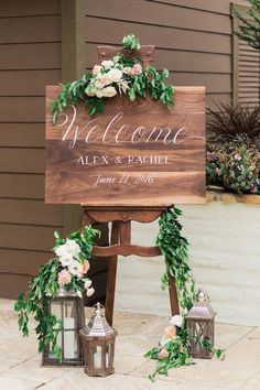 a welcome sign with flowers and greenery on it