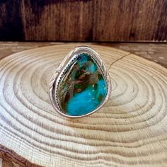 CHUNKY TURQUOISE A wonderful turquoise landscape ring featuring a large triangle shape stone with beautiful brown matrixing. The stone is set in a sawtooth bezel surrounded by a wider flat piece of silver that has some unique hammer marks on both sides. Split band and polished with a nice patina in areas for the vintage look. HALLMARK: J, Sterling DIMENSIONS:   ring size: 12 face: 1 1/8" x 1 1/4" WEIGHT: 14g MATERIALS:  sterling silver and turquoise COLOR: silver and blue CONDITION: excellent! Southwestern Chrysocolla Gemstone Rings, Southwestern Turquoise Chrysocolla Ring, Southwestern Chrysocolla Turquoise Ring, Southwestern Teardrop Turquoise Gemstone Ring, Southwestern Teardrop Turquoise Ring, Southwestern Style Teardrop Turquoise Ring, Southwestern Jewelry, Triangle Shape, Turquoise Color