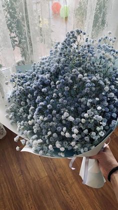 a bouquet of blue flowers sitting on top of a glass table next to a window