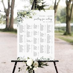 a wedding seating sign with flowers and greenery on the top is shown in front of trees