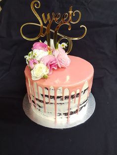 a pink and white cake with flowers on top that says sweet sixteen in gold lettering