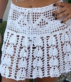 a woman wearing a white crochet skirt with her hand on her hip pocket