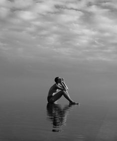 a man sitting on the water with his head in his hands