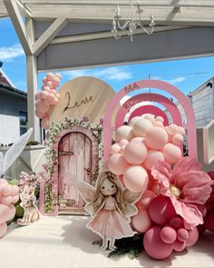 an outdoor area with balloons, flowers and fairy figurines