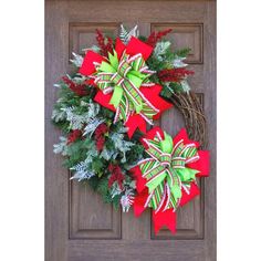 two christmas wreaths on the front door with green and red bows hanging from them