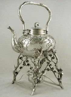 a silver tea pot with flowers on it