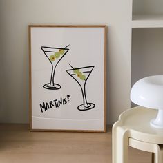 two martini glasses with olives in them are on the table next to a lamp