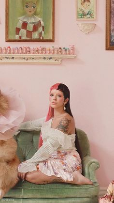 a woman sitting on top of a green couch next to a dog in a pink room