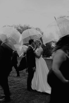 a bride and groom kissing under clear umbrellas