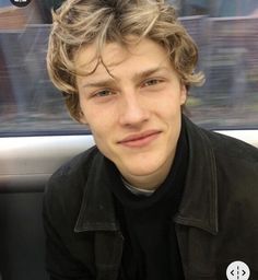 a young man sitting in the back seat of a car looking at the camera with a serious look on his face