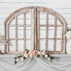 an old window is decorated with flowers and pearls on the mantelpiece, along with other decorations