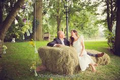 a bride and groom sitting on hay bales