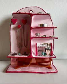 an open pink purse with jewelry on it's sides and hanging from the inside