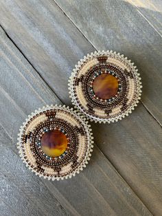 two brown and white beaded cupcakes sitting on top of a wooden table