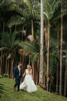 a bride and groom walking through palm trees