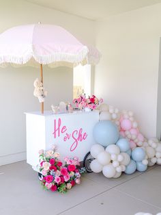 an ice cream stand with balloons and flowers on the ground, next to a pink umbrella