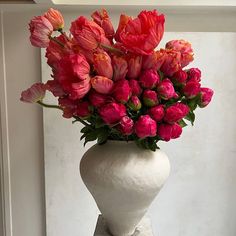 a white vase filled with red and pink flowers