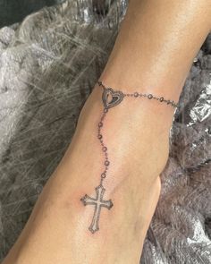 a woman's foot with a cross and heart tattoo on the side of her leg