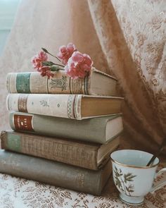 a stack of books sitting on top of a table next to a cup and saucer