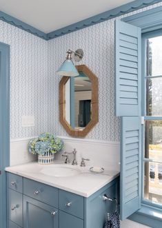 a bathroom with blue and white wallpaper, two sinks and a large mirror on the wall