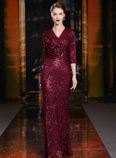 a model walks down the runway in a red sequinned gown with long sleeves