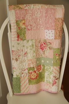 a white chair with a pink and green quilt on it