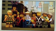 a group of lego people standing next to each other in front of a cityscape