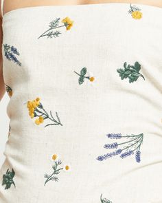 the back of a woman's white top with yellow and blue flowers on it