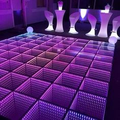 an illuminated dance floor with vases in the middle and lights on each one side