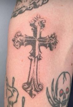 a cross and skull tattoo on the arm