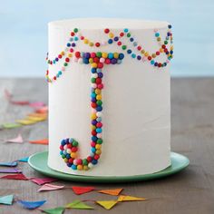 a white cake decorated with multicolored candies and the letter j on it