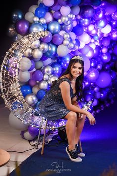 a woman is sitting on a chair in front of balloons that are all around her