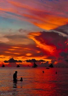 people are swimming in the ocean at sunset