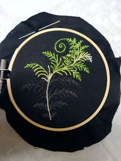 a black bag with a green plant embroidered on the front and side, sitting next to a pair of scissors