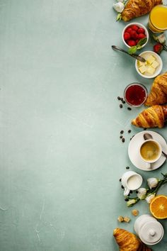 croissants, orange slices and other breakfast foods arranged on a blue background