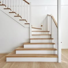 a white staircase with wooden handrails in an empty room